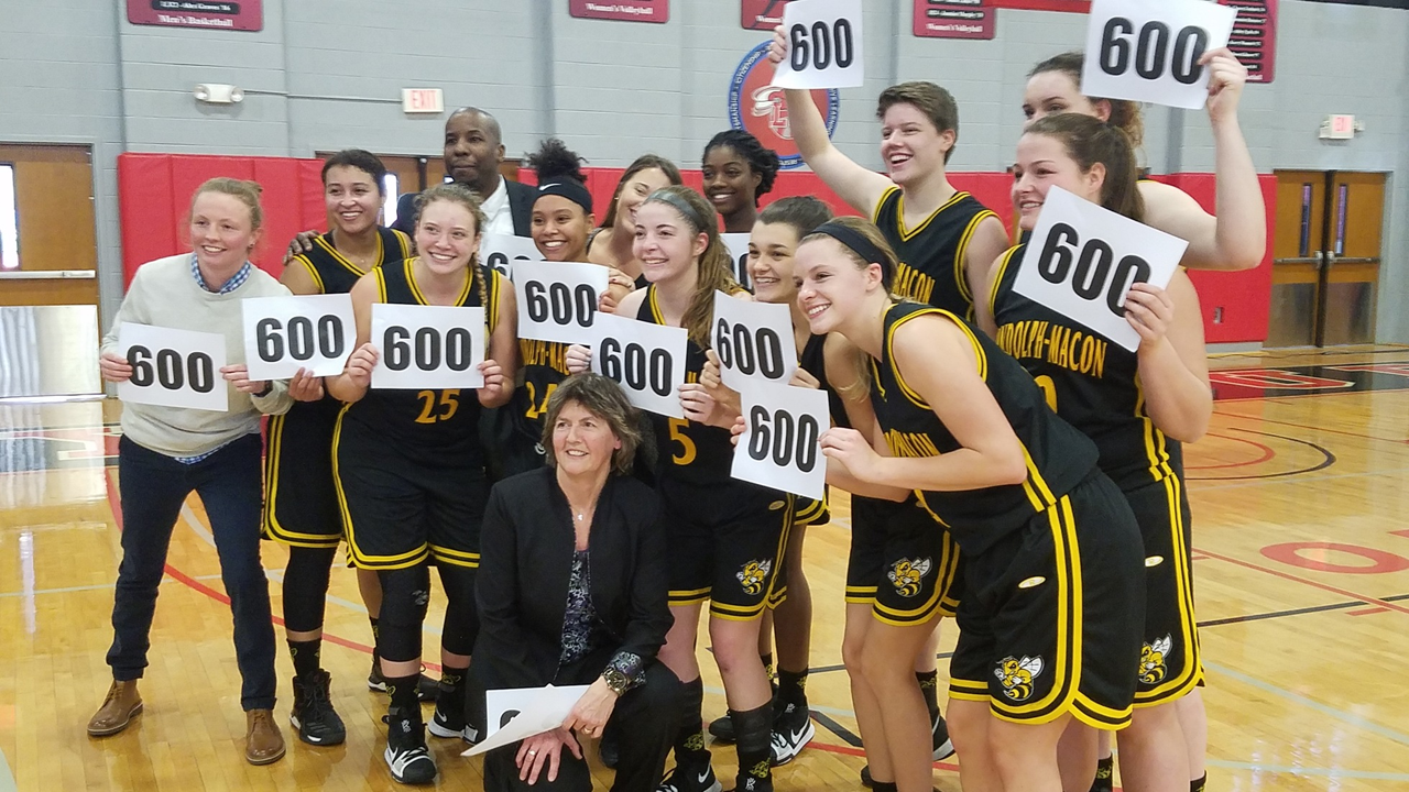 Randolph-Macon women's basketball poses with 600 signs to commemorate the 600th career victory for head coach Carroll LaHaye.